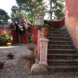 L�atrio dell�abitazione dove spiccano i vivaci colori di fiori, piante e vasi in terracotta disposti sulla scala che conduce agli interni